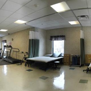 A spacious rehabilitation room equipped with a treadmill and therapy beds, designed for physical therapy sessions.