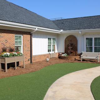 A serene outdoor space featuring a pathway, manicured lawn, and flower beds.