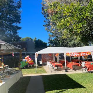 A festive outdoor party setup with a large tent and colorful decorations under a clear blue sky.