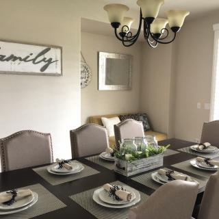 A modern dining room with a neatly arranged table setting and elegant chandelier.