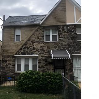 A residential house with a stone facade and a small front yard.