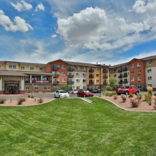 A modern apartment complex with a well-maintained lawn under a cloudy sky.