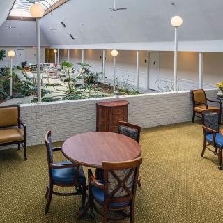 A cozy indoor seating area with tables and chairs overlooking a well-lit space.