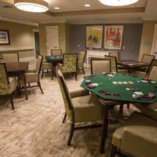 A poker room with multiple card tables and chairs, ready for a game.