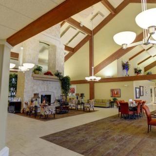 A spacious lobby with high ceilings, featuring a cozy fireplace and a dining area.