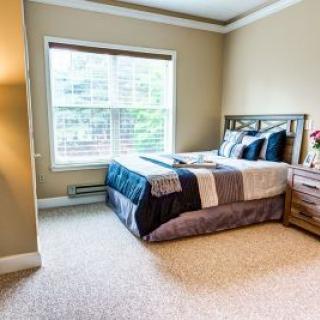 A cozy bedroom with a neatly made bed and a large window.