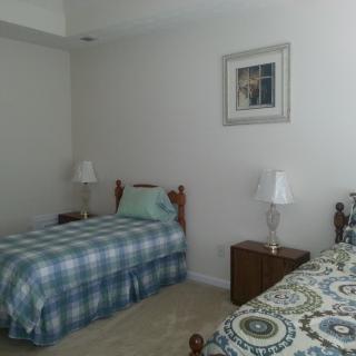 A bedroom with two twin beds, each adorned with different patterned bedspreads. A small wooden nightstand sits between the beds, topped with matching lamps.