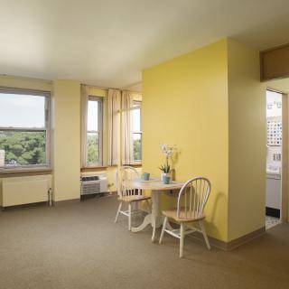Bright apartment dining area with yellow walls and natural light.