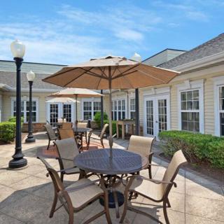 A sunny patio area with a table, chairs, and umbrellas outside a building.