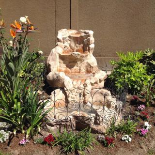 A beautifully arranged garden landscape featuring a rock formation surrounded by a variety of flowers and plants.