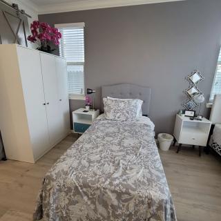 A cozy bedroom with a single bed, wardrobe, and decorative elements.