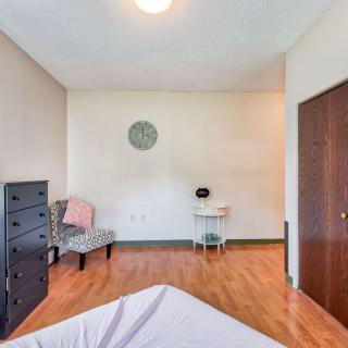 A minimalist bedroom with a dresser, chair, and wooden flooring.