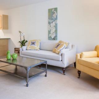 A modern living room with a gray sofa, yellow armchair, and a metal coffee table.
