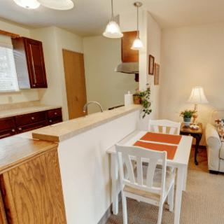 A cozy kitchen and dining area with wooden cabinets and a small dining table set for two.