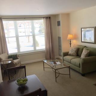 A cozy living room with a comfortable sofa, coffee table, and large window allowing natural light.