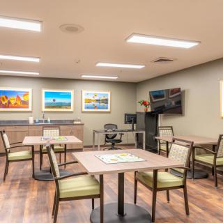 A modern meeting room with tables, chairs, and colorful artwork on the walls.