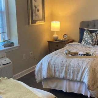 A cozy bedroom with a neatly made bed, warm lighting, and a window.