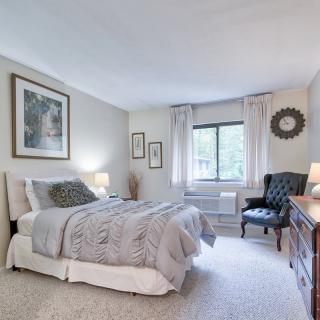 A cozy and elegantly decorated bedroom featuring a comfortable bed, armchair, and stylish decor.