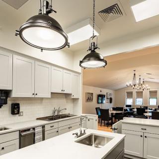 A modern kitchen featuring white cabinetry, an island counter with a sink, and stylish pendant lighting.
