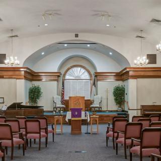 Interior view of a church with rows of pews and a central podium.
