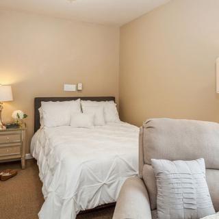 Cozy bedroom with a bed, nightstand, and upholstered chair.