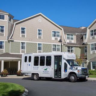 A small shuttle bus parked in front of a multi-story residential building.