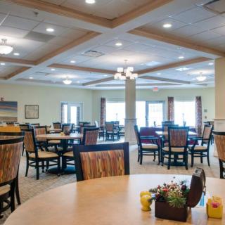 A spacious dining area with multiple tables and chairs, featuring elegant lighting and decor.