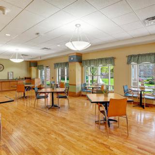 A spacious dining area featuring wooden flooring and ample natural light, designed for comfort and social interaction.
