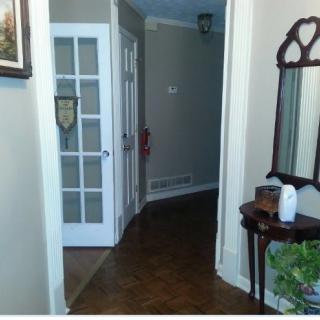 A hallway with a decorative mirror and table next to a door.