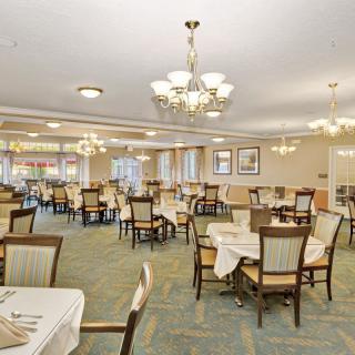 An elegant dining room with neatly arranged tables and chairs under stylish chandeliers.