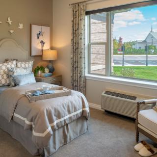 A cozy bedroom with a single bed, stylish decor, and a large window offering a scenic view.