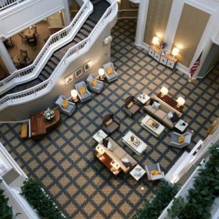 A spacious and elegant lobby with a seating area, featuring a grand staircase and soft lighting.