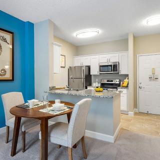 A modern apartment featuring a compact kitchen and cozy dining area with contemporary furniture.