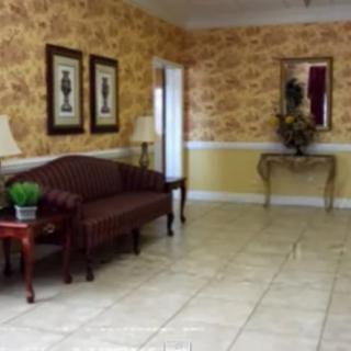 A cozy lobby area with elegant decor, featuring a sofa, side tables, artwork, and a mirror.
