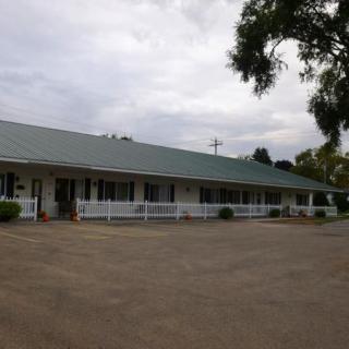A rural motel building with a parking lot in front and trees nearby.