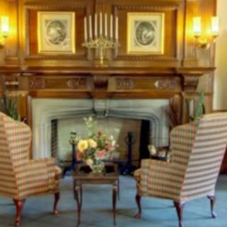 A cozy living room with a classic fireplace, adorned with striped armchairs and decorative art.