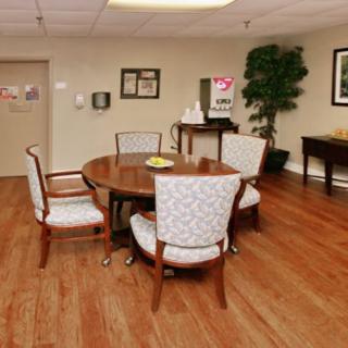 A cozy room interior with a wooden table and chairs, featuring hardwood flooring and decorative elements.