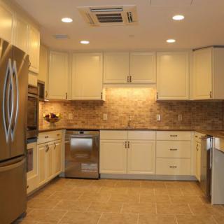A modern kitchen with beige cabinets, stainless steel appliances, and tile flooring.