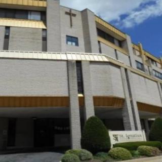 A modern religious building with a prominent cross on its facade under a partly cloudy sky.