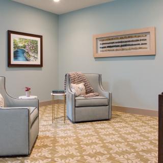 A cozy living room with armchairs and artwork on the walls.