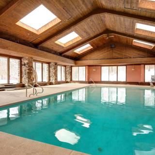Spacious indoor swimming pool with skylights and a wooden ceiling.