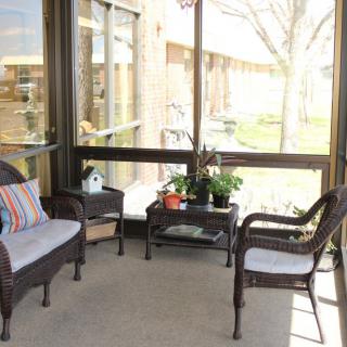 A cozy screened-in porch with wicker furniture and potted plants.
