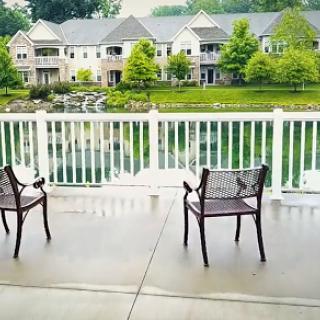 A serene view from a balcony overlooking a tranquil waterfront and charming homes.
