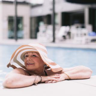 A woman enjoying a relaxing moment by the swimming pool, wearing a stylish sun hat.