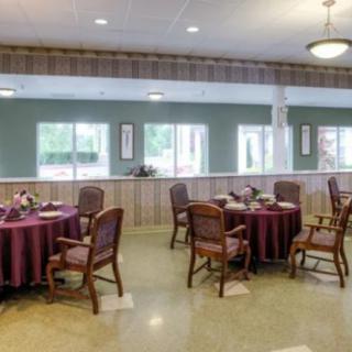 A cozy dining area with round tables, wooden chairs, and large windows allowing natural light to fill the room.
