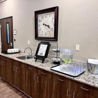 A reception area with a beverage station and clock on the wall.