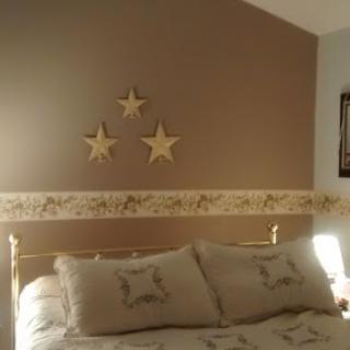 A cozy and inviting bedroom featuring elegant bedding and charming star decorations on the wall.