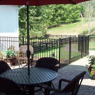 A cozy patio with a table and chairs under an umbrella, overlooking a garden and fenced yard.