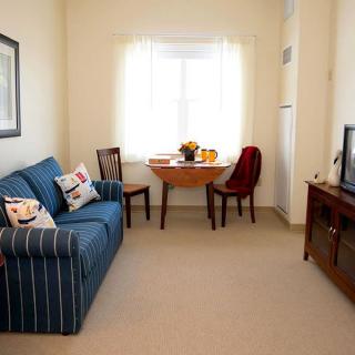 A cozy living room with a blue striped sofa, dining table, and television.