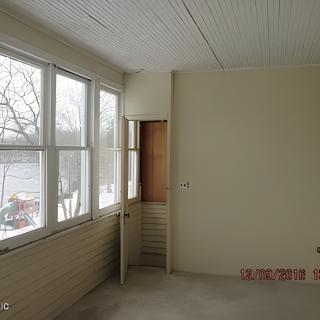 An empty sunroom with large windows and beige walls.